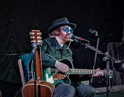 Musician playing acoustic guitar on dimly lit stage